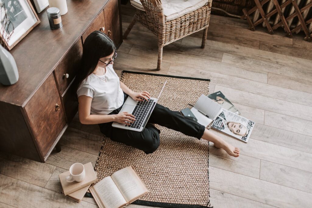 A cozy scene of a blogger working at a laptop with coffee, surrounded by sticky notes, books and and chair.